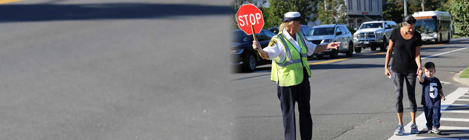 a crossing guard helping a mother and her son cross the street